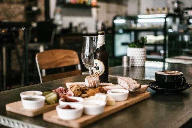 Daska sa predjelima, boca piva i šolja kafe na stolu u kafiću
